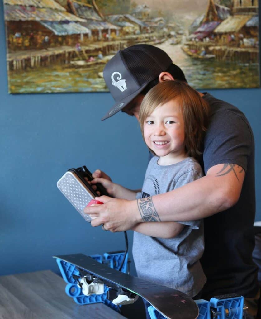 Child helping dad wax skis at home, featured in a post about ski gift ideas for dads on That’s La Plagne.
