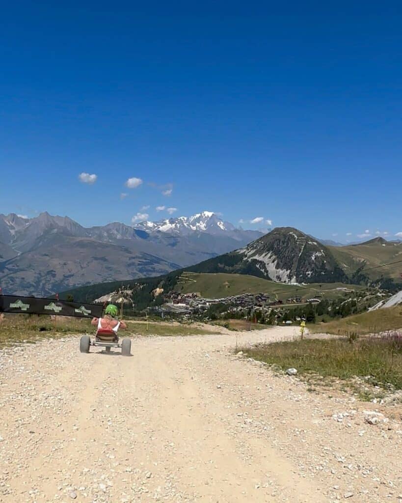 POV mountain carting down a dusty alpine track in Montalbert with panoramic mountain views towards Mont Blanc.