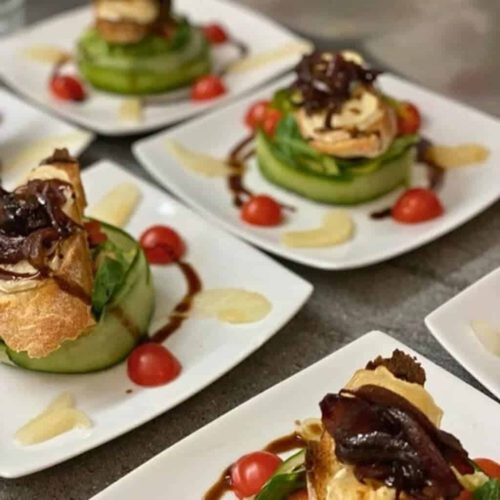 Gourmet Starter Dish from Will I Ski La Plagne – Elegant appetizer plates featuring a cucumber-wrapped salad, cherry tomatoes, caramelized onions, and toasted bread topped with creamy cheese, drizzled with balsamic glaze.