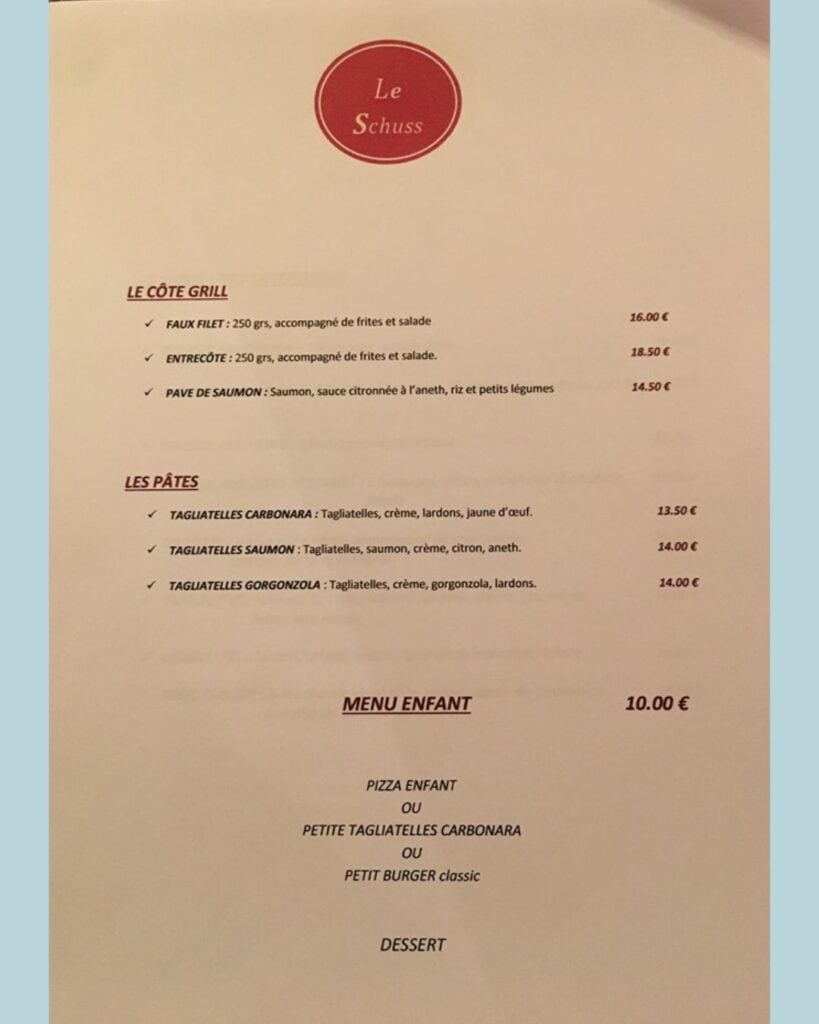 Menu from Le Schuss restaurant listing grilled dishes like faux filet, entrecôte, and salmon, plus pasta options such as tagliatelle carbonara, salmon, and gorgonzola, along with a kids’ menu.
