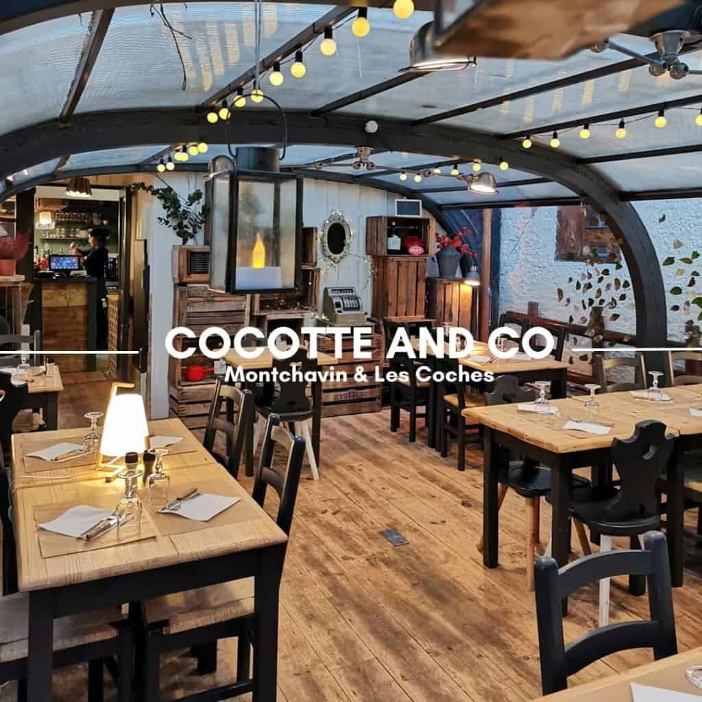 A stylish, cozy restaurant with wooden tables, warm lighting, and a greenhouse-style glass ceiling decorated with string lights. The rustic interior features wooden accents, plants, and vintage décor. The text overlay reads "Cocotte and Co, Montchavin & Les Coches."