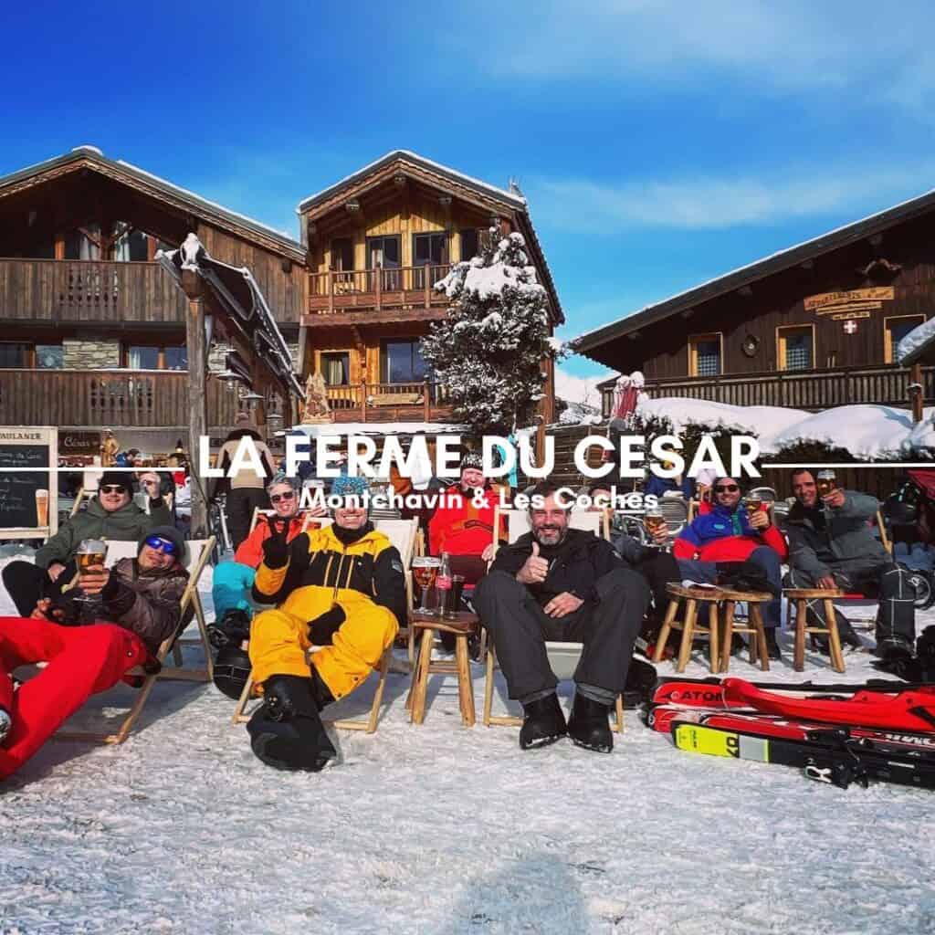 A group of skiers and snowboarders in colorful winter gear lounge on deck chairs outside a chalet-style restaurant, enjoying drinks in the sunshine. The wooden buildings in the background, covered in snow, add to the lively après-ski atmosphere. The text overlay reads "La Ferme du Cesar, Montchavin & Les Coches."