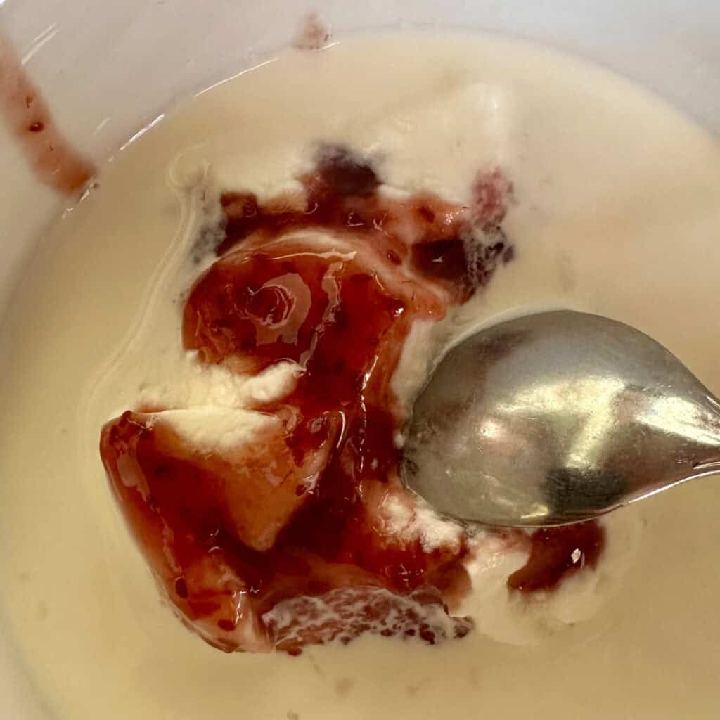 Close-up of a creamy white dessert with berry compote being spooned, served at Chalet du Plan Bois—simple, rich, and comforting.