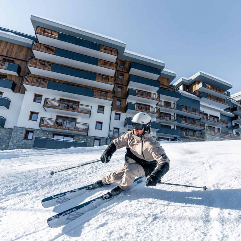 Man carves through fresh powder right outside a ski-in/ski-out hotel, ideal for those seeking the best accommodation Plagne Centre for direct access to the pistes.