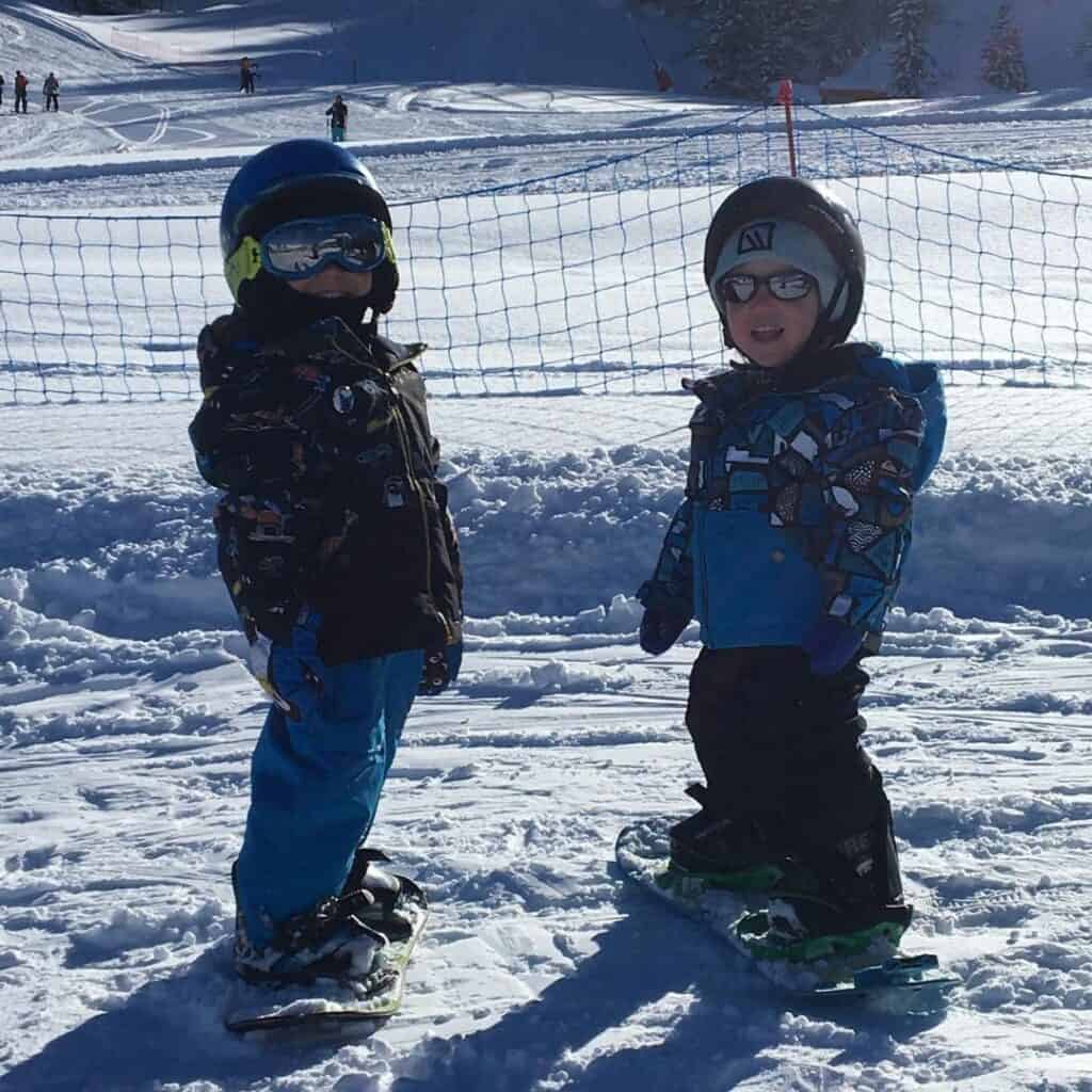 Two young kids on snowboards stand side by side on a snowy slope at La Plagne, reinforcing how beginner-friendly the resort is for both skiing or snowboarding.
