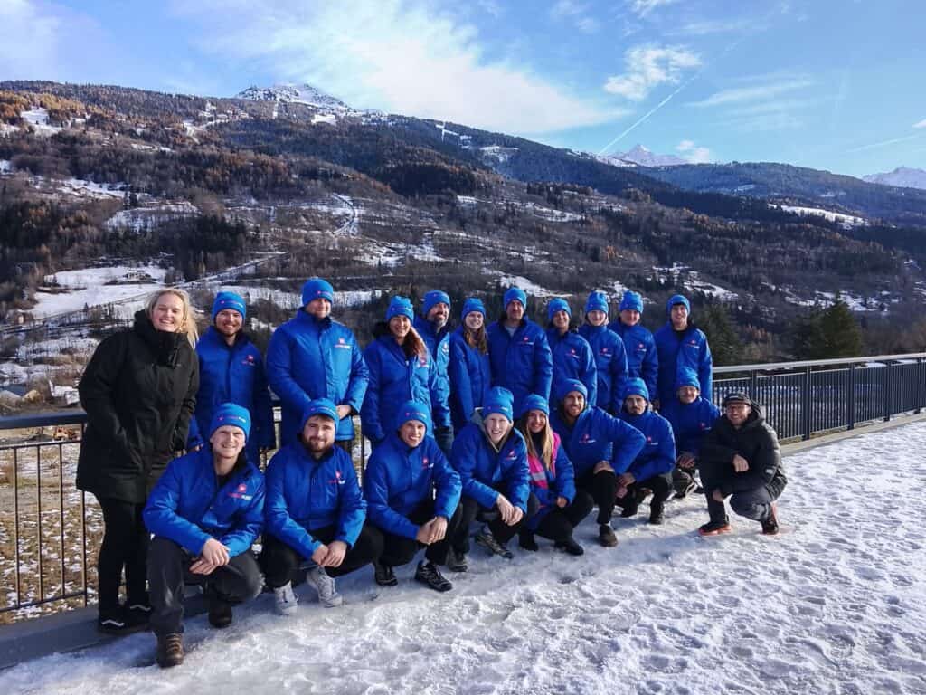 Alpine Fleet resort representatives wearing blue branded winter jackets posing together in a snowy French Alpine ski resort