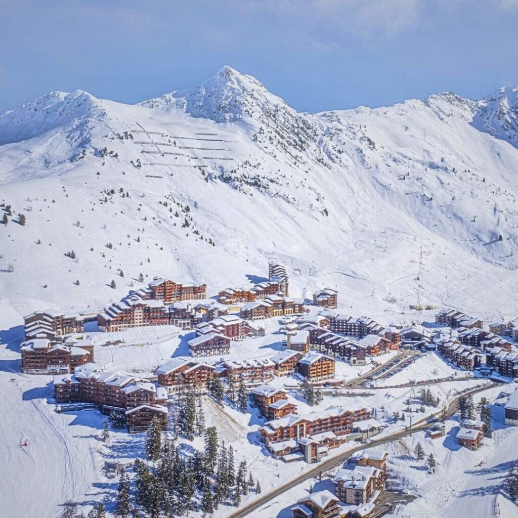 High-angle view of Belle Plagne’s accommodation nestled at the base of snowy peaks, highlighting the variety of the best accommodation Belle Plagne for ski holidays.