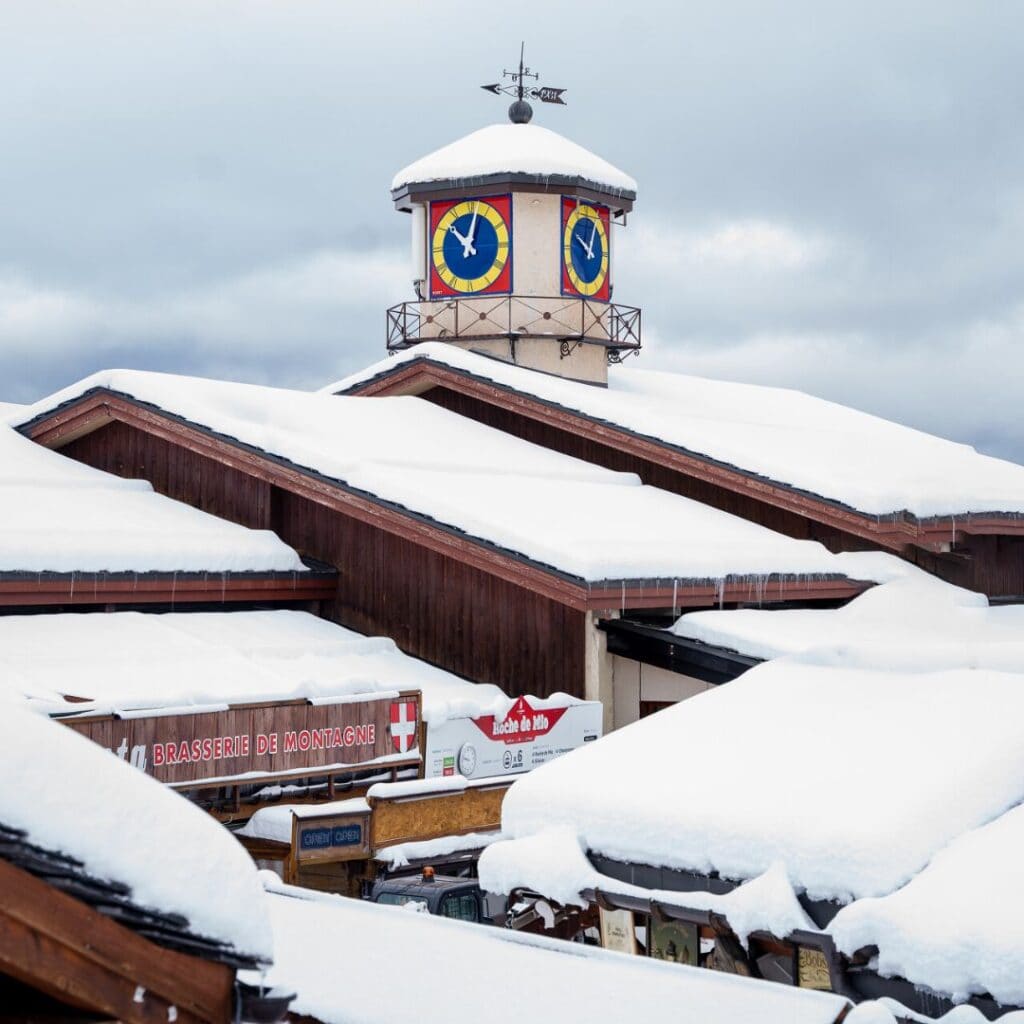The colorful clock tower in Belle Plagne’s village center rises above snow-dusted rooftops, located near the best accommodation Belle Plagne for easy access to shops and dining.