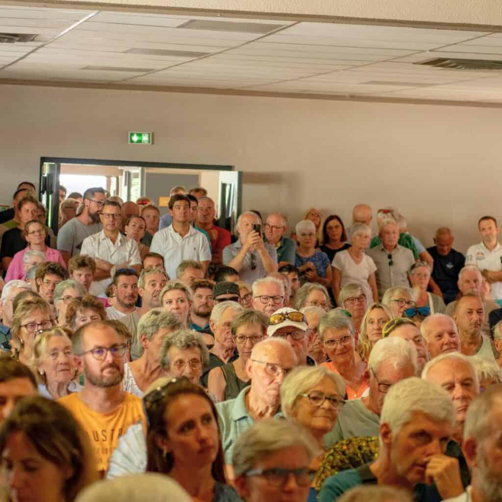 A large audience listens intently during a packed meeting about the new lift La Plagne and the Aime La Plagne gondola project, showing strong local interest.
