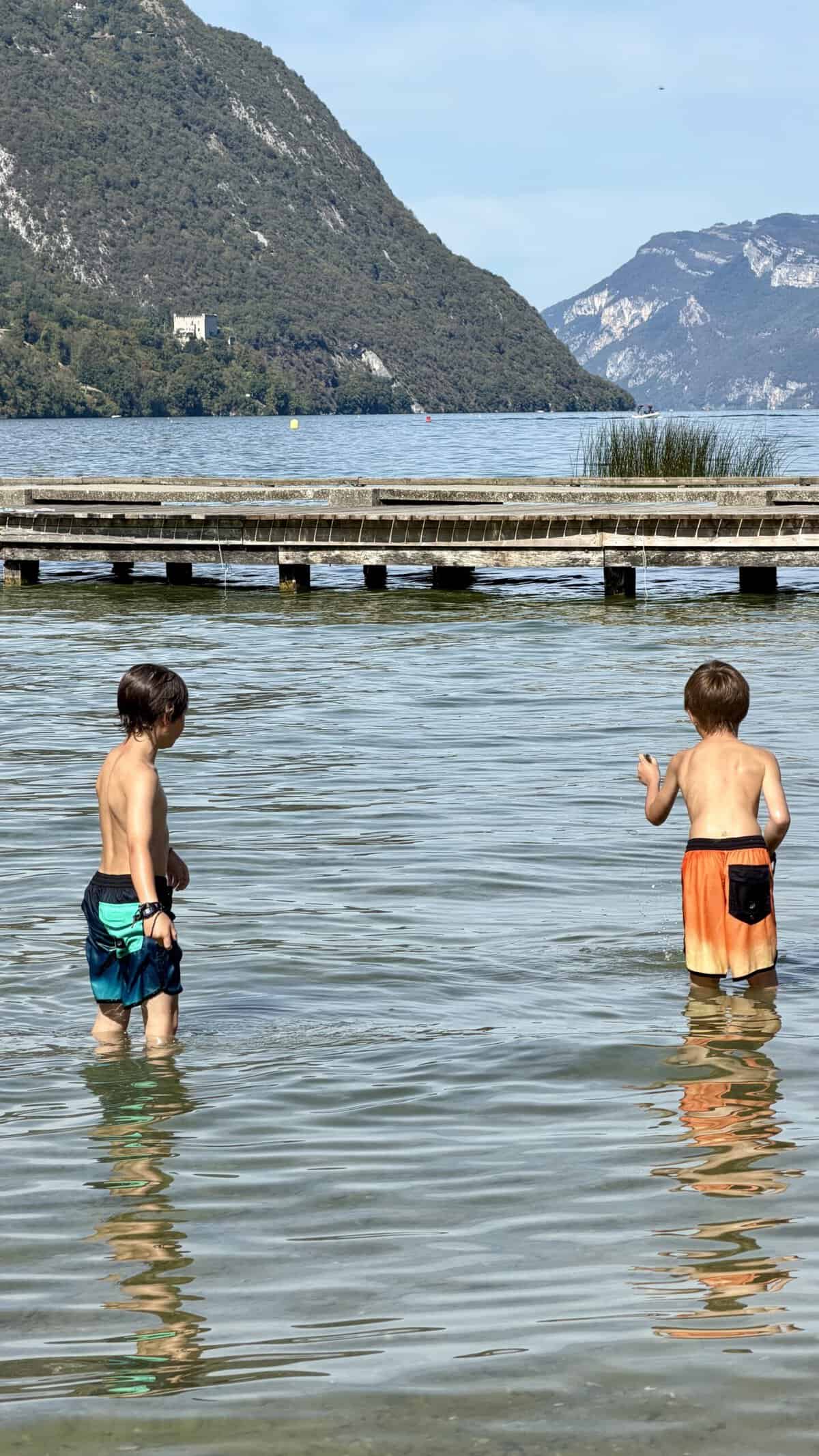 Lake day with 2 young boys in the lac du bourget, playing in the water witha wooden jetty in the distance
